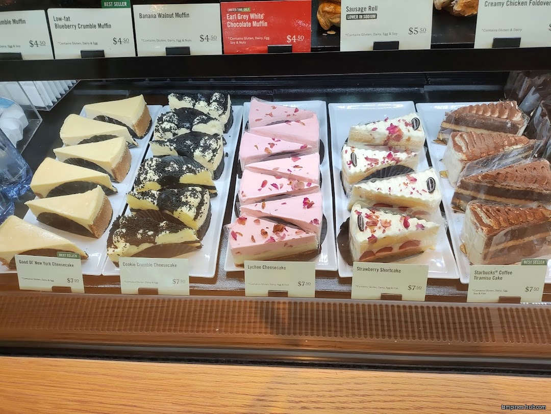 A display case shows various cake slices and muffins at Starbucks.