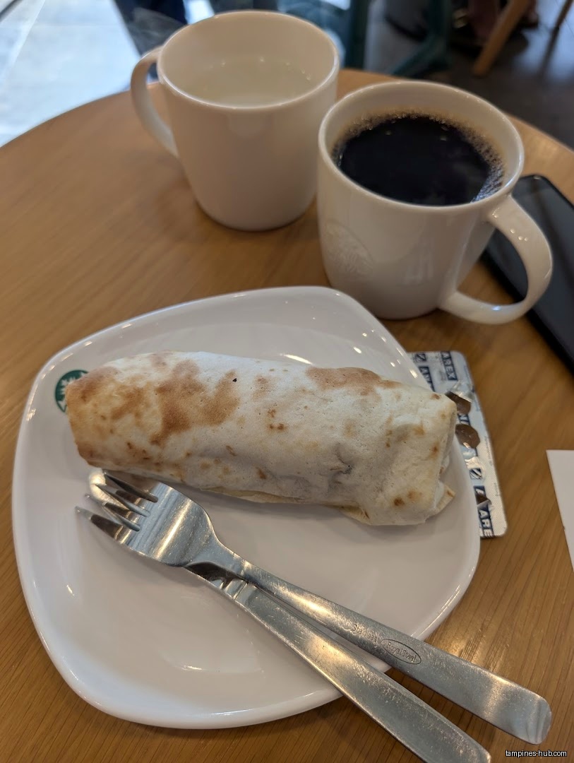 A Starbucks burrito, coffee, and water are on a table.