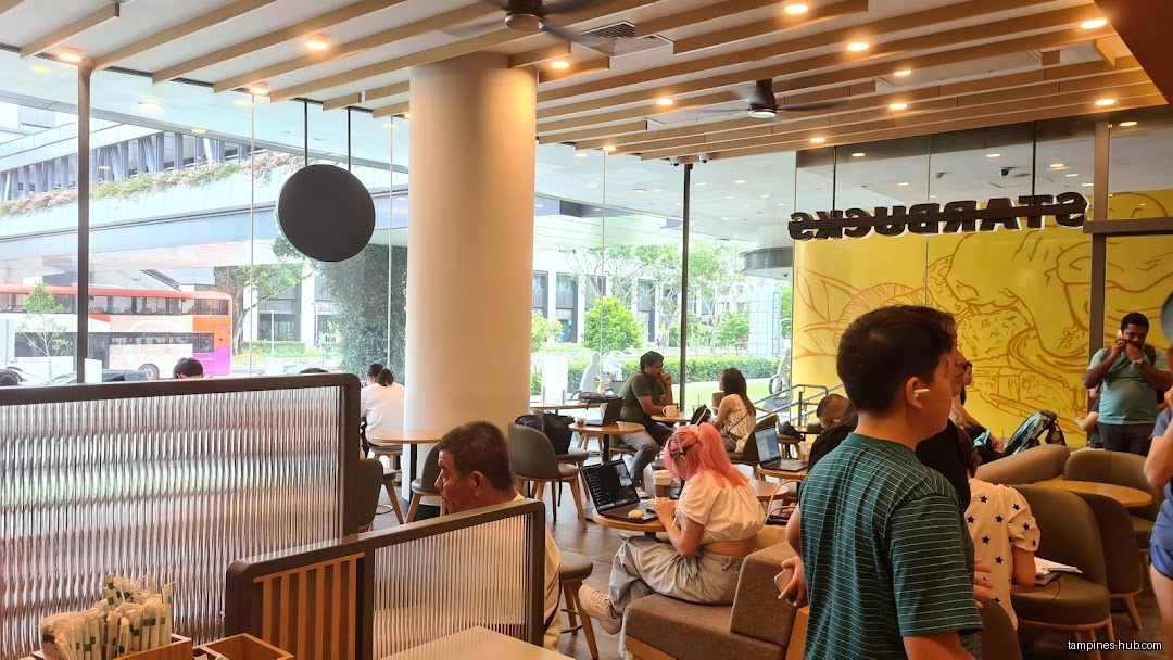 The image shows the interior of a Starbucks with customers and furniture.