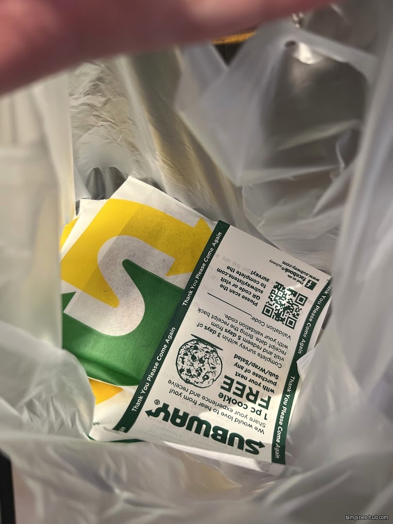 A Subway sandwich wrapper and a coupon inside a plastic bag.