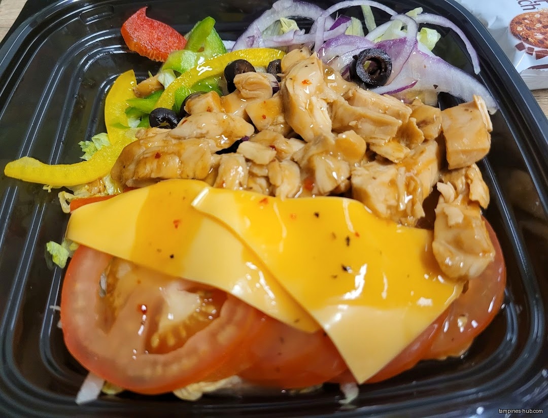 A Subway salad with chicken, cheese, tomatoes, onions, and peppers.