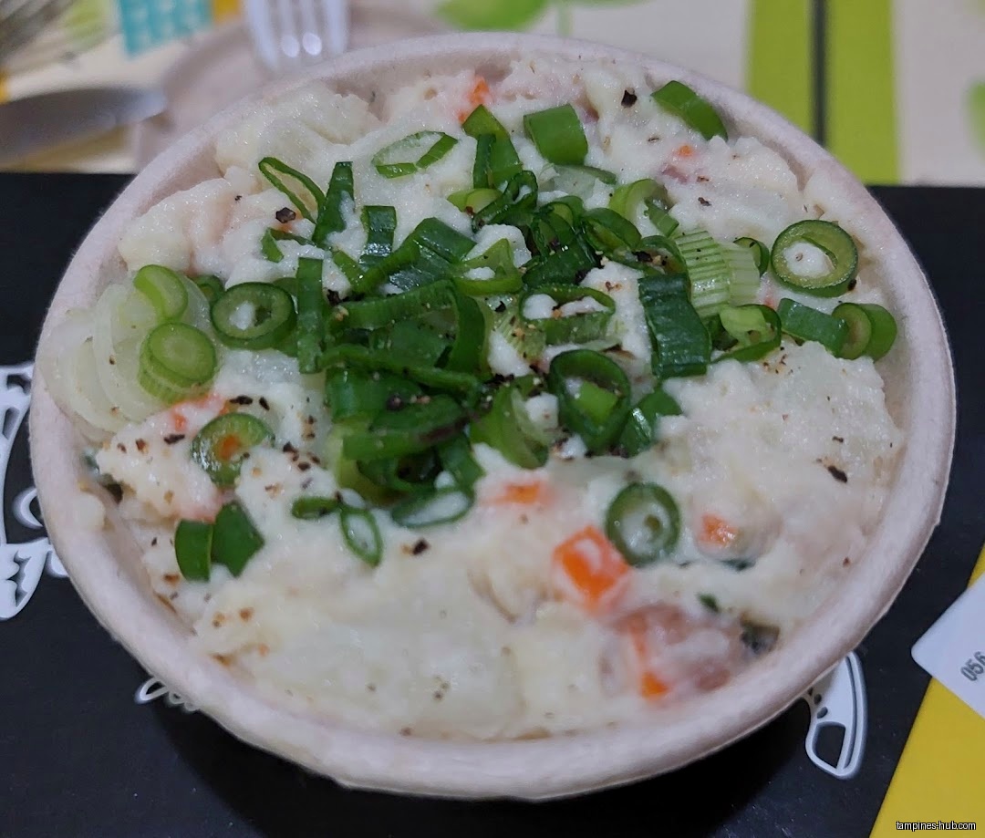 Close-up of a bowl of potato salad topped with green onions.