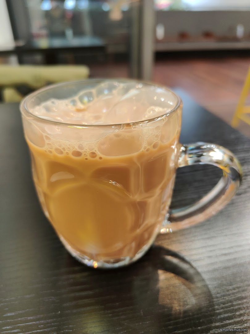 A glass mug filled with coffee sits on a dark table.