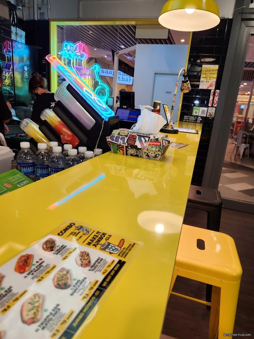A yellow counter with drinks, menu, tissues, and stools at Super Sub.