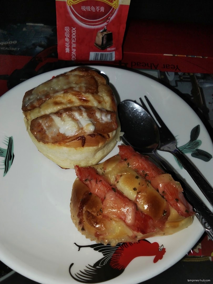 Two buns with toppings on a plate with a spoon and fork.