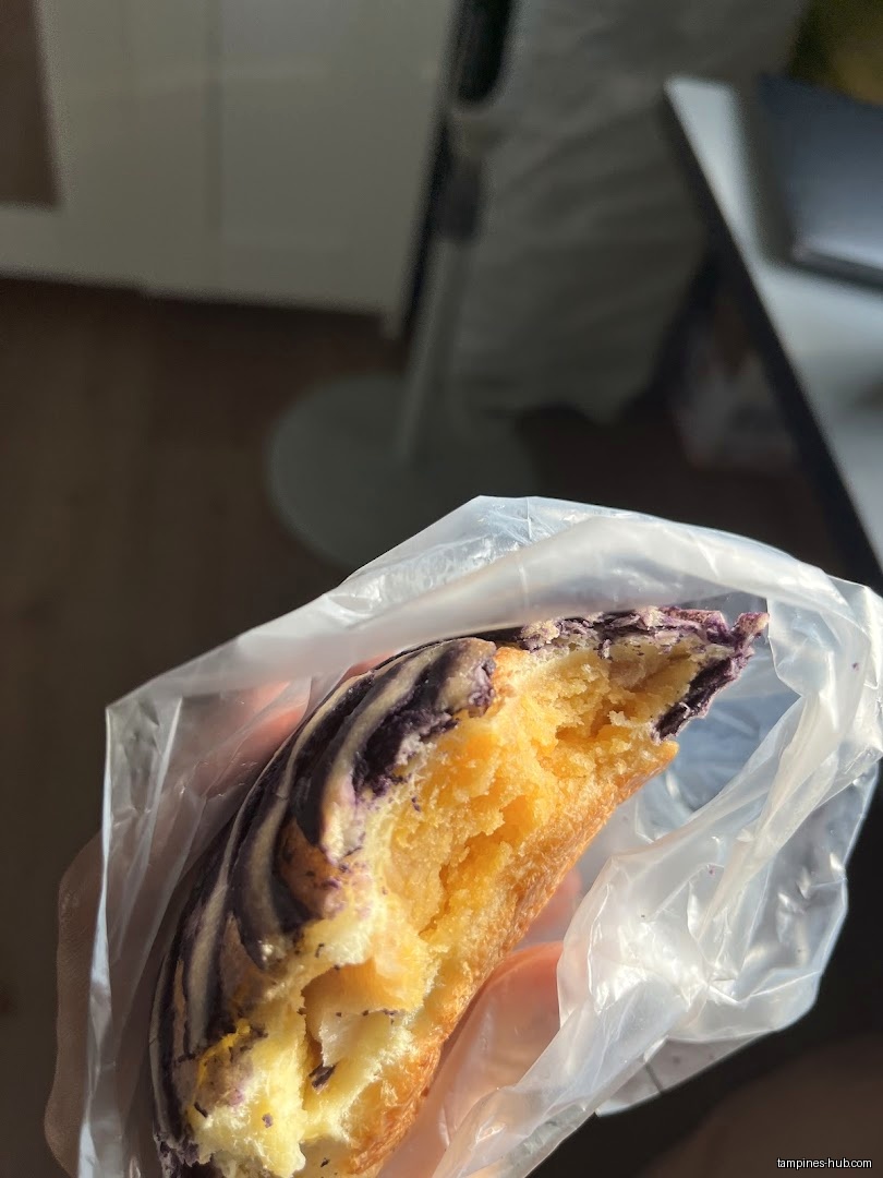 A half-eaten pastry with purple icing in a plastic bag.