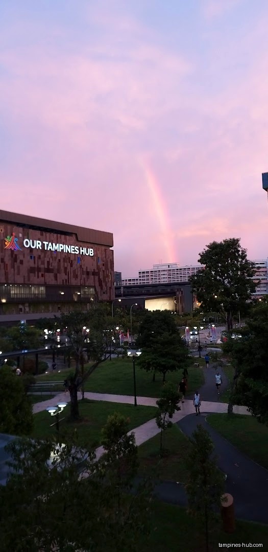 Our Tampines Hub building with a rainbow in the sky at dusk.