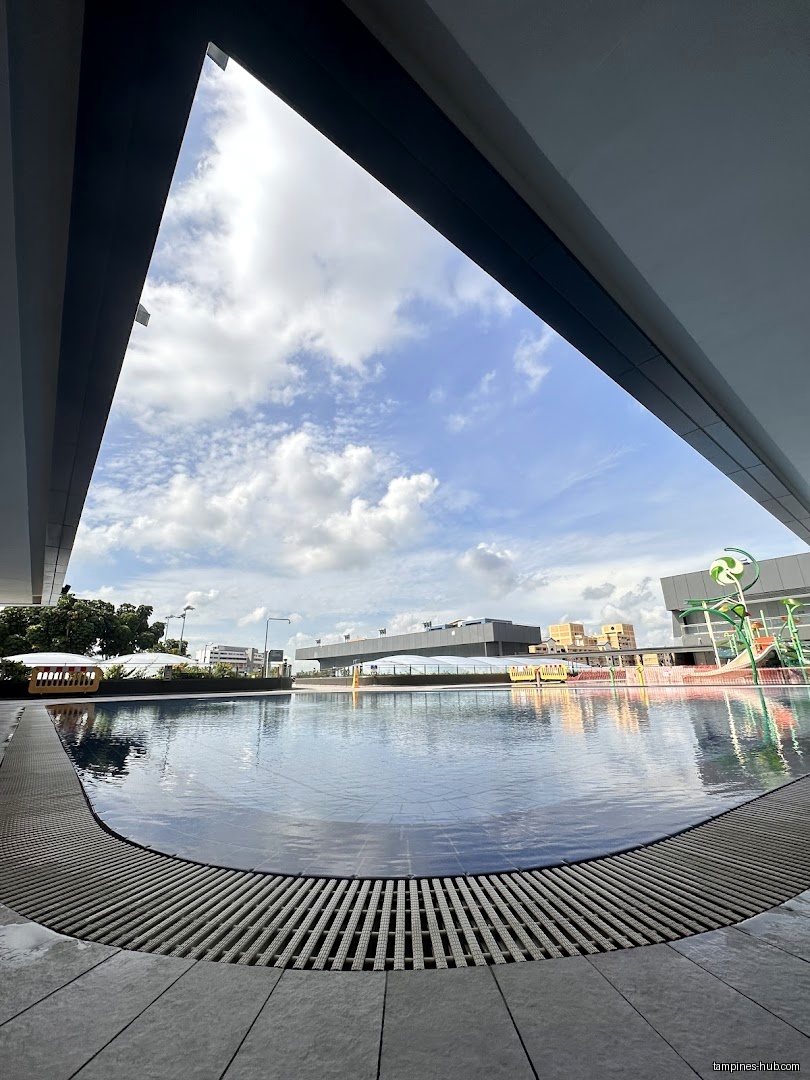A view of a swimming pool and the sky from under a building.
