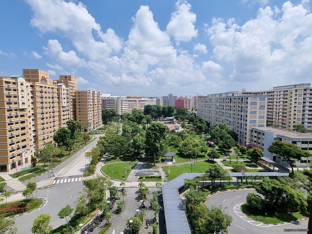 The image shows a park and residential buildings under a cloudy sky.