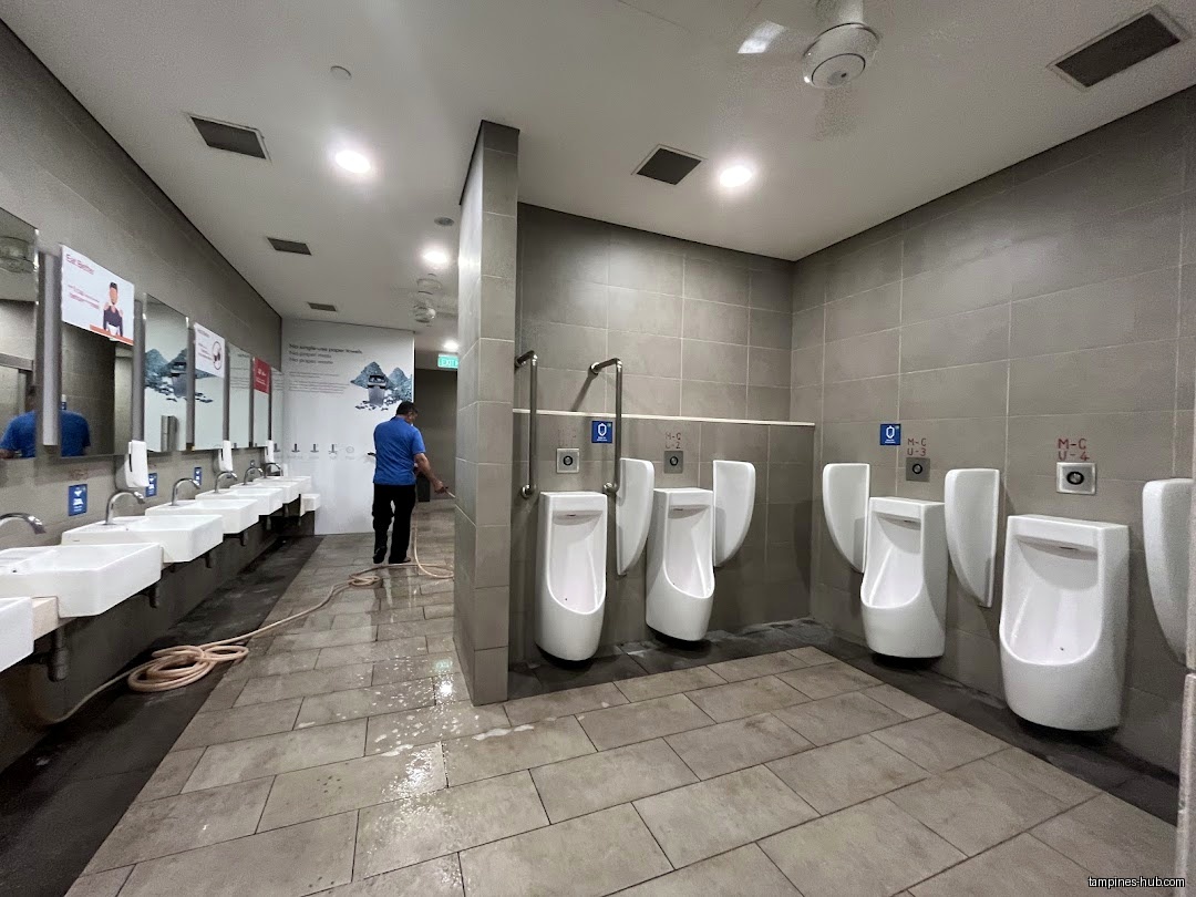 A man is cleaning the restroom with urinals and sinks.