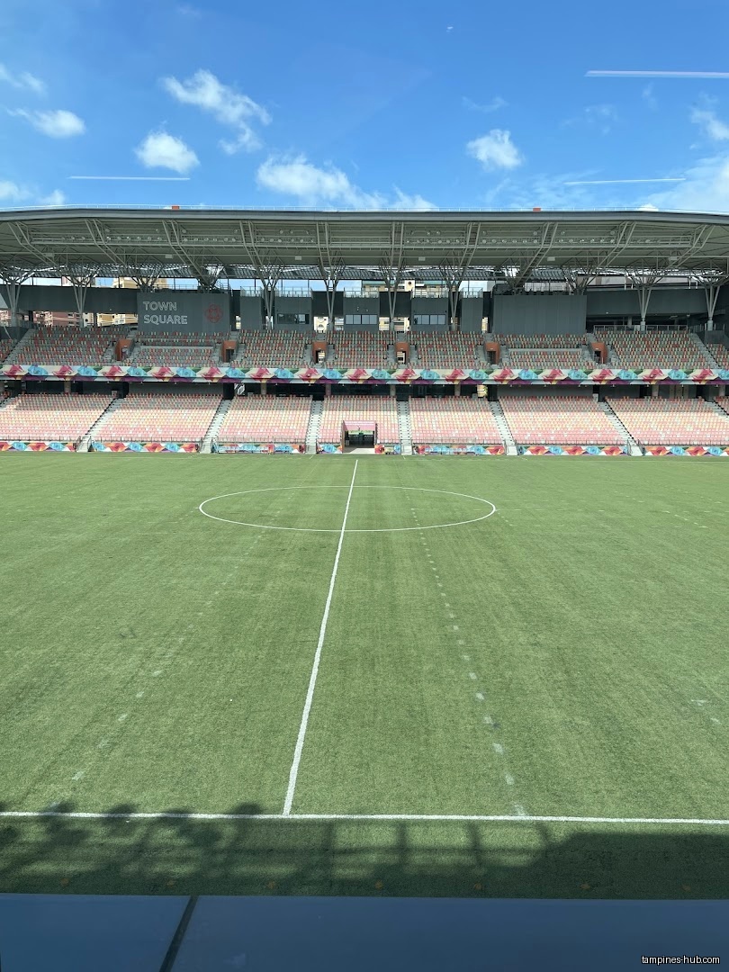 A soccer field with stadium seating under a blue sky.