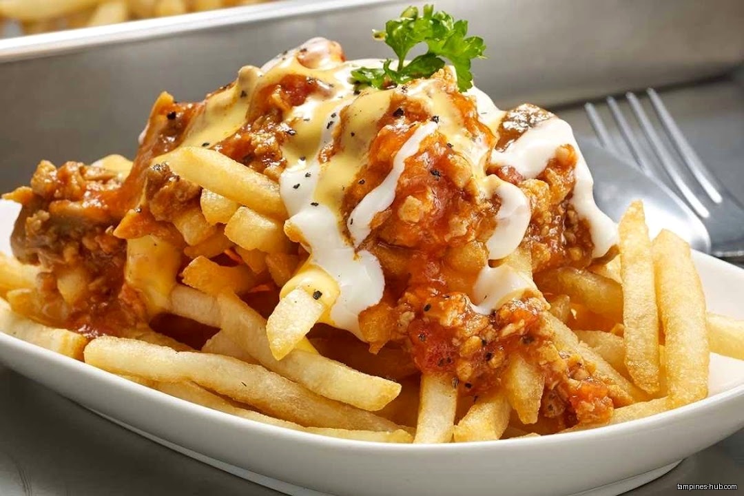 A plate of french fries topped with sauce and a garnish.
