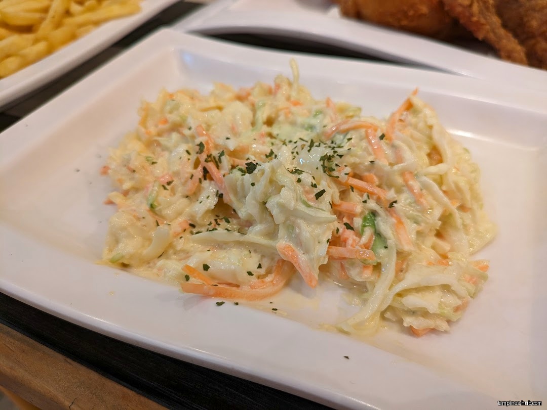 A plate of coleslaw is shown, with fries and fried chicken visible.