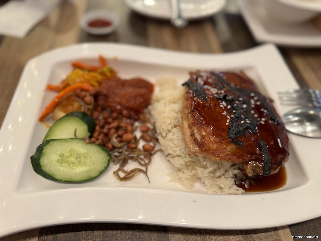 A plate of Nasi Lemak with chicken, peanuts, and vegetables is shown.