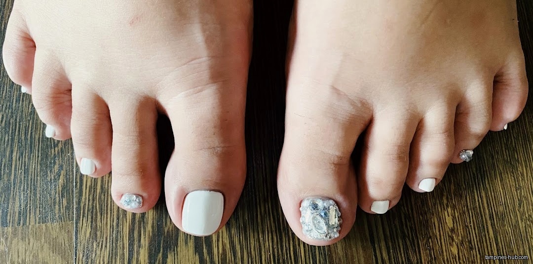 Close-up of two feet with painted toenails, one with embellishments.