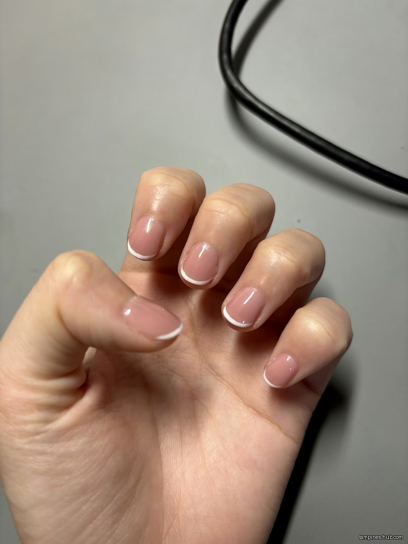 A hand with a fresh set of French manicure nails is displayed.