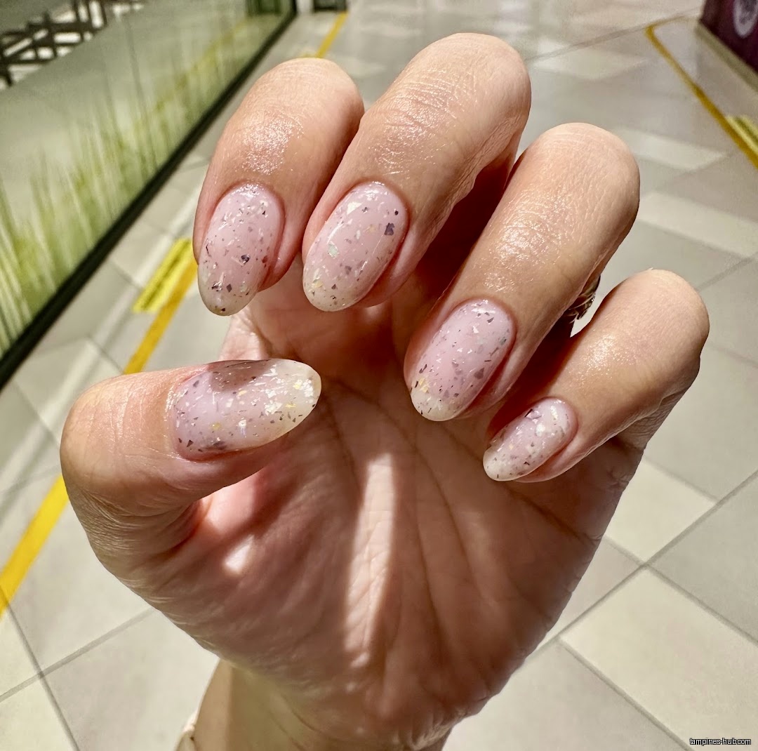 A hand with oval nails painted with a glittery, speckled design.