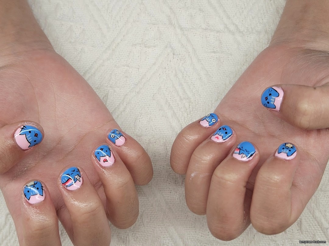 Hands with pink and blue cartoon character nail art on a white background.