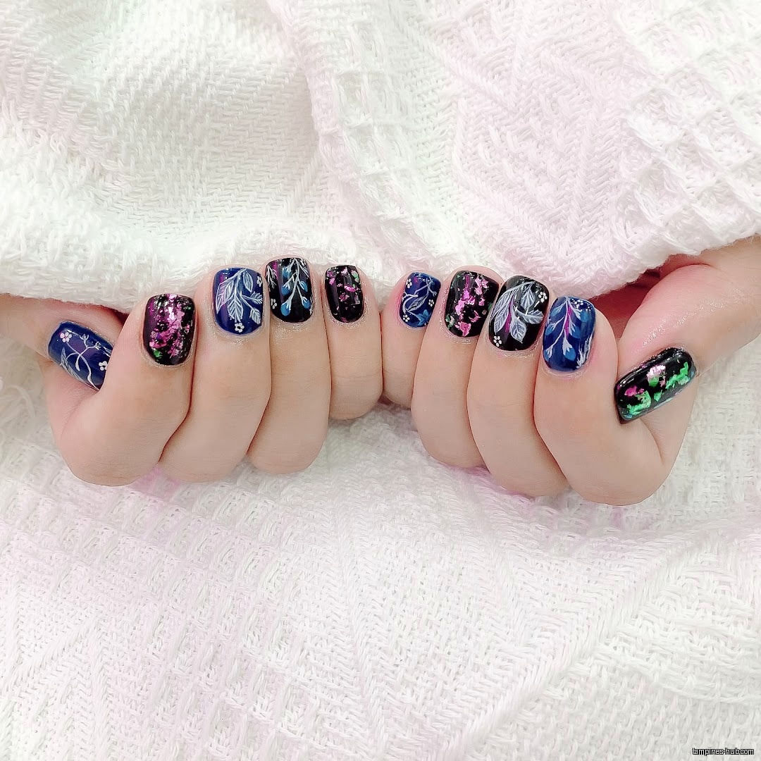 Close-up of hands with floral and glitter nail art designs.