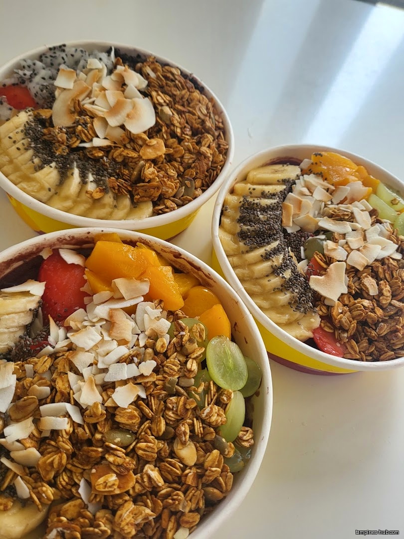 Three bowls of açaí with fruit, granola, and coconut flakes are displayed.