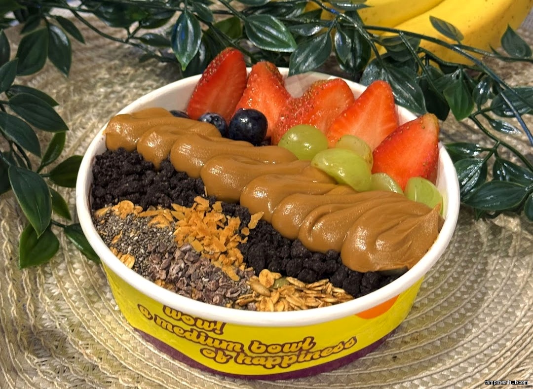 Açaí bowl with strawberries, grapes, blueberries, peanut butter, and other toppings.