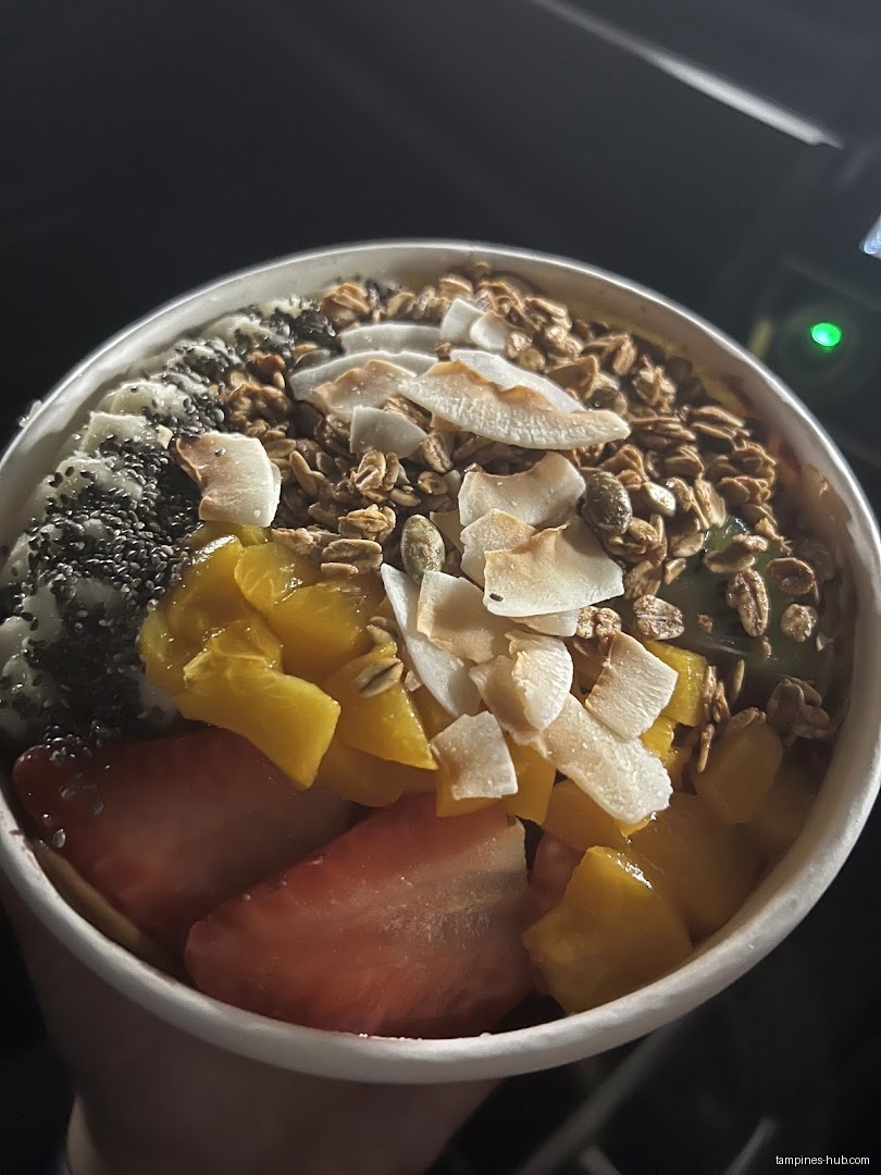 Açaí bowl with strawberries, mango, coconut flakes, granola, and chia seeds.