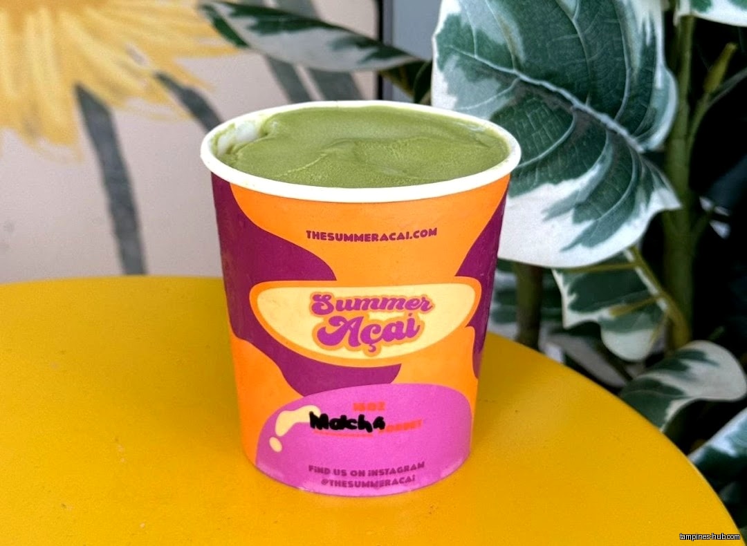 A cup of matcha açaí from The Summer Açaí on a yellow table.