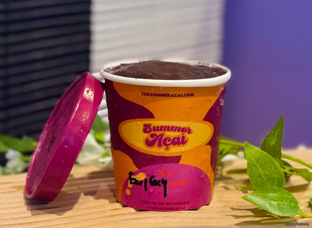 A cup of Summer Açaí with the lid off, on a wooden surface.