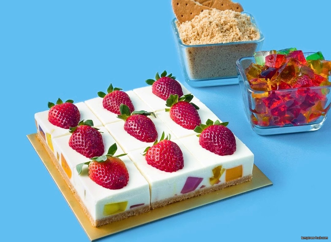 A jelly cake topped with strawberries, graham cracker crumbs, and jelly cubes.