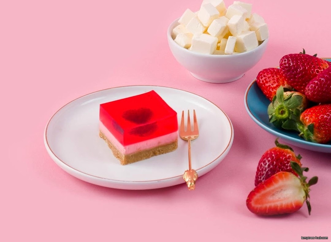Jelly cake, strawberries, and cream cubes are displayed on a pink background.