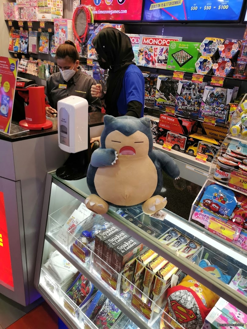 Timezone shop interior with staff, prizes, and a Snorlax plush toy.