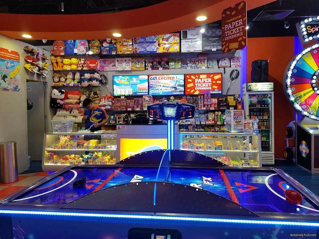 Timezone arcade interior with air hockey table, prizes, and staff member.