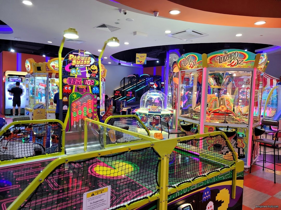 The image shows the interior of an arcade with various game machines.