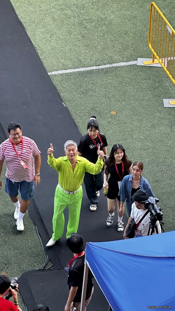 A group of people walking on a black runway with a camera crew.