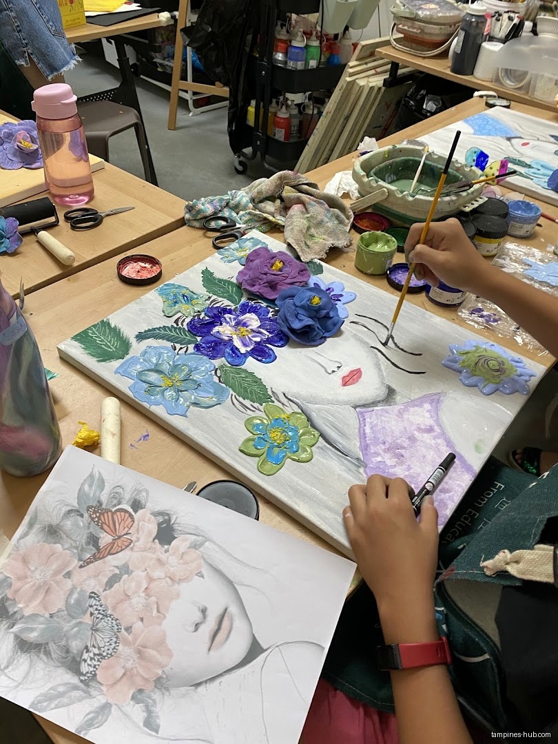 A child paints a floral portrait in an art class setting.