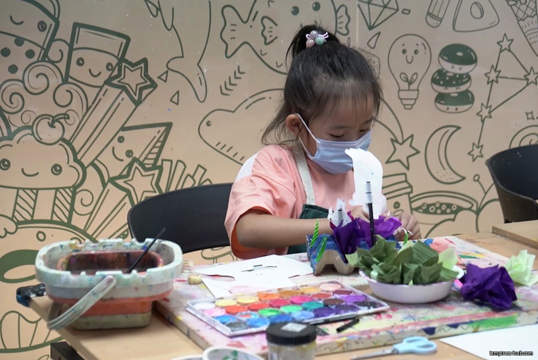 A young girl wearing a mask is doing an art project.