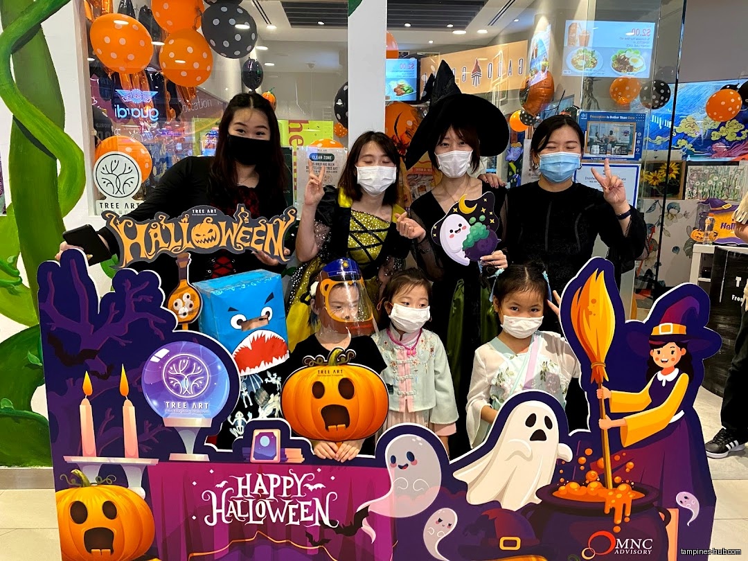 Staff and children pose with a Halloween-themed cutout at Tree Art.