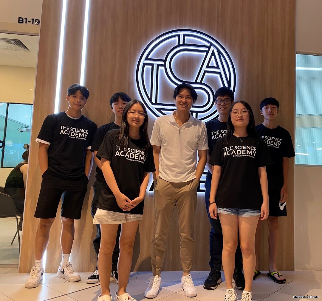 Group of people posing in front of TSA THE SCIENCE ACADEMY logo.
