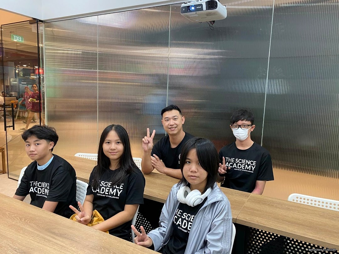 Group of students and teacher wearing matching shirts in a classroom.