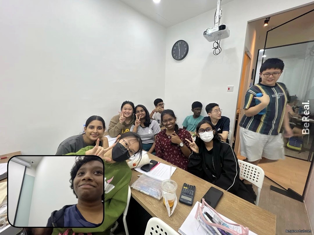 A group of students are posing in a classroom setting, some making peace signs.