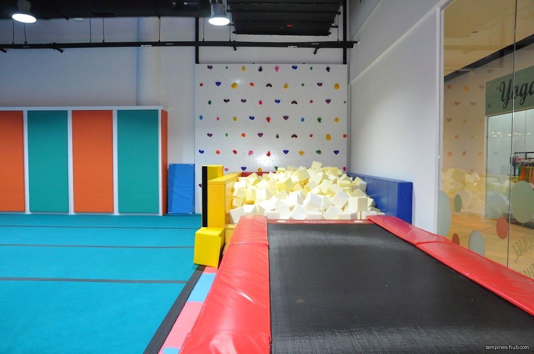 Gymnastics area with trampoline, foam pit, and climbing wall inside the shop.