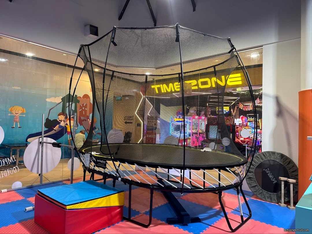 A trampoline with a safety net is set up inside the gymnastics shop.