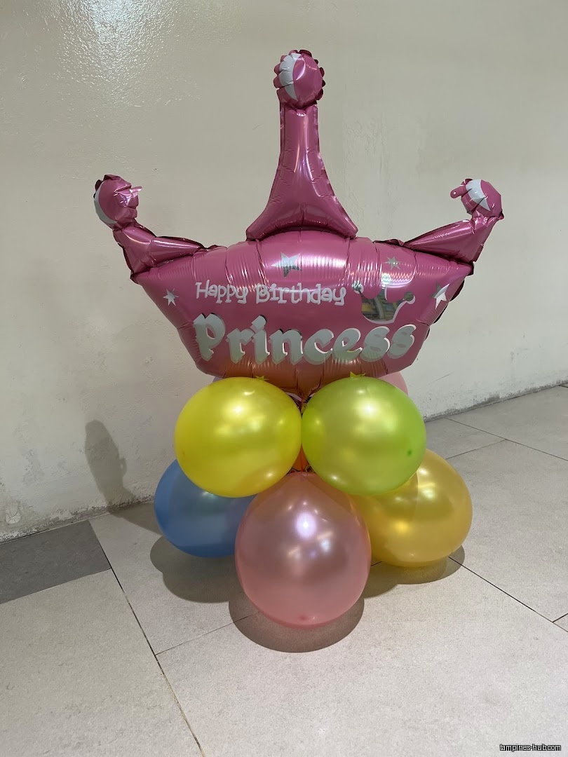 A balloon arrangement with a pink crown balloon and colorful round balloons.