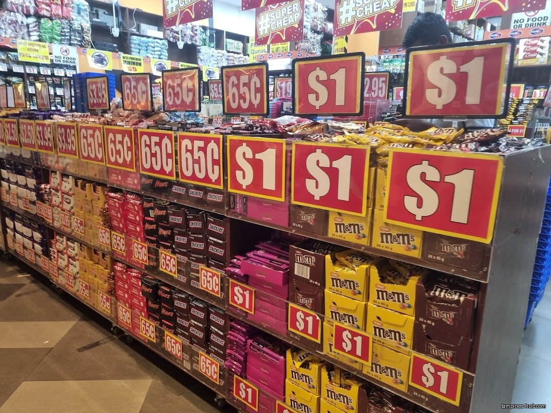 Shelves stocked with candy bars and chocolates, with price signs above them.