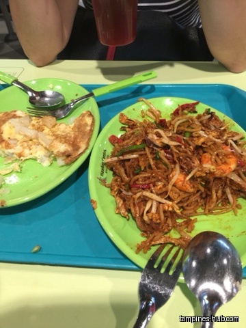 Two plates of food, one with noodles and shrimp, the other with eggs.