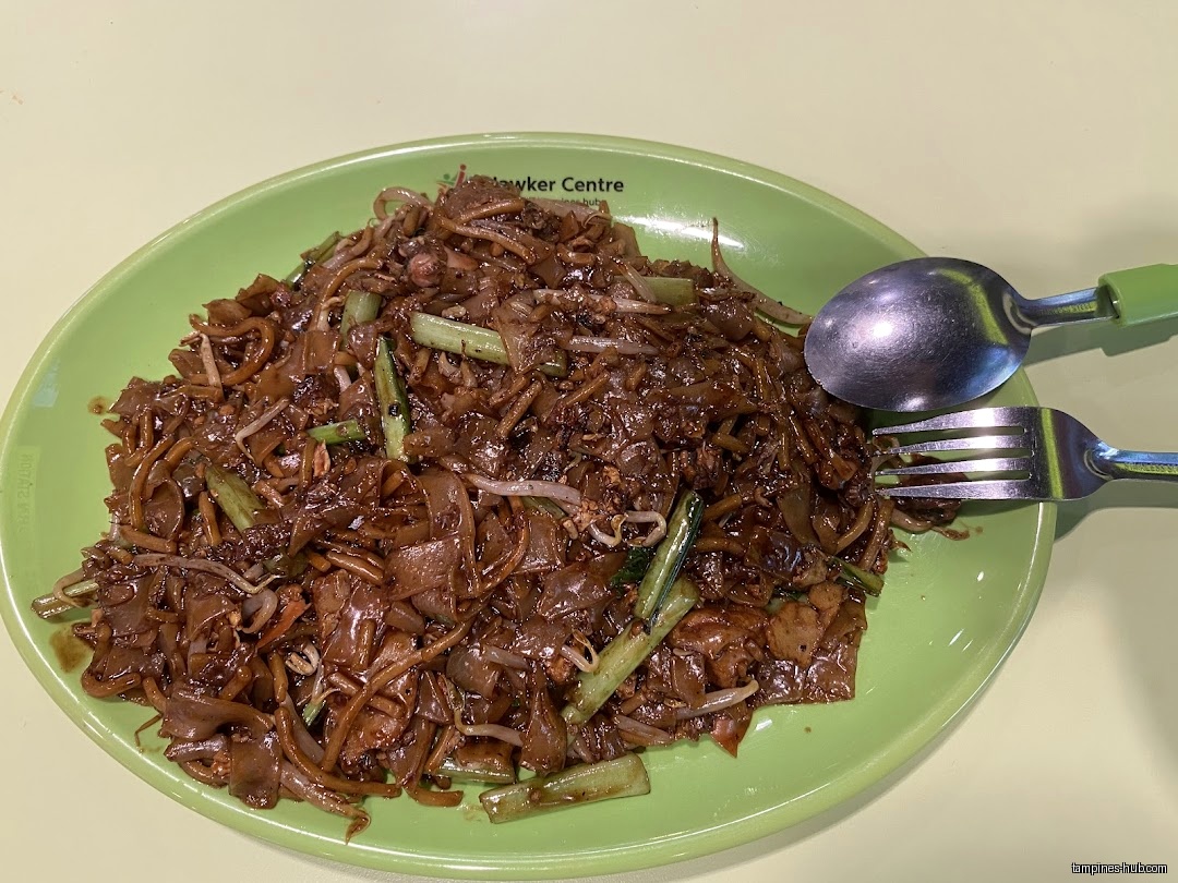 A plate of Char Kway Teow with a spoon and fork.