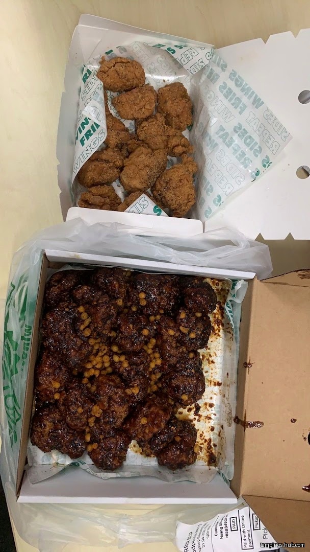 Two boxes of Wingstop wings, one with plain wings and one with sauce.