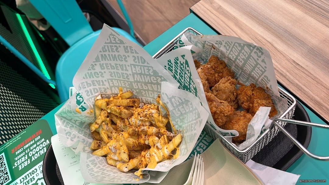 A basket of fries with cheese and a basket of chicken wings.