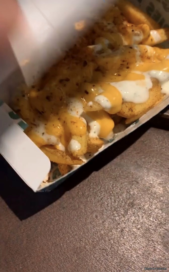 A box of fries topped with cheese and white sauce.