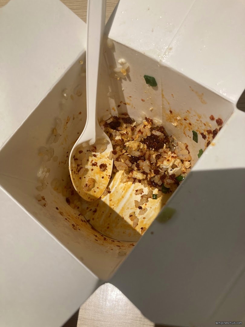A nearly empty Wok Hey takeout box with a spoon inside.